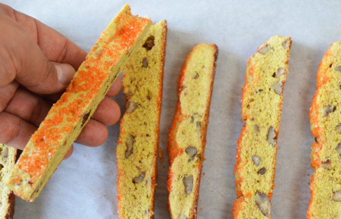 Using a serrated knife cut the baked biscotti dough. The place the sliced biscotti back on the tray to back a second time. 